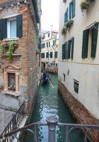 navigable channel between houses of Venice and gondola typical boat to transport tourists to Italian island
