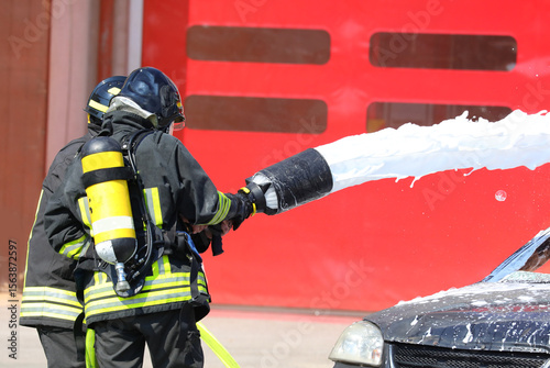 Team of uniformed firefighters during   incident extinguishing operations after   road accident