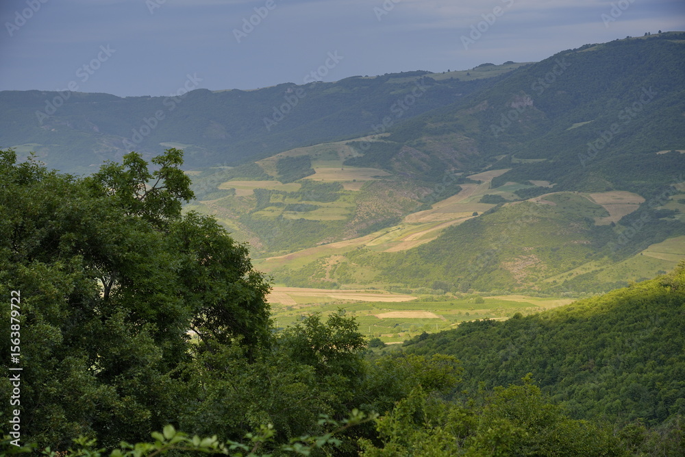 Fototapeta premium Forested hills and valley under clouds