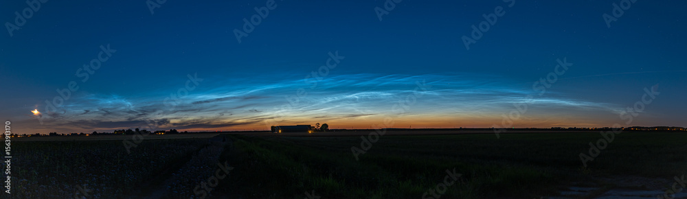Fototapeta premium Panorama of noctilucent clouds (NLC) over the wide open Dutch countryside on a clear evening in late June.