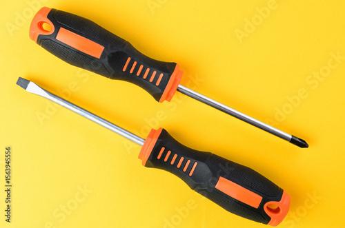 Phillips and flathead screwdrivers metal hand tools on bright yellow background top view