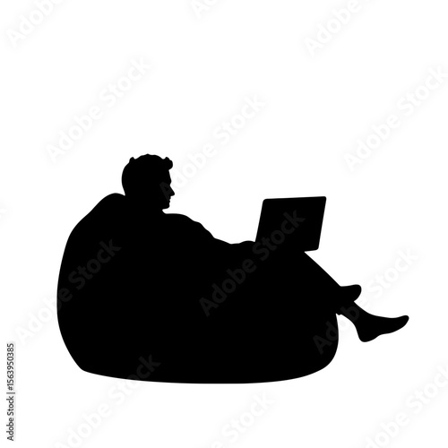 Man sitting on bean bag while working on laptop at home  