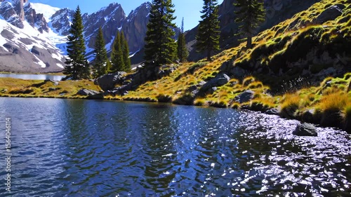 Serene alpine lake mirroring sunlight, crystal waters nestled among snow dusted mountains, towering pines, golden autumn landscape stretching beneath vivid sky