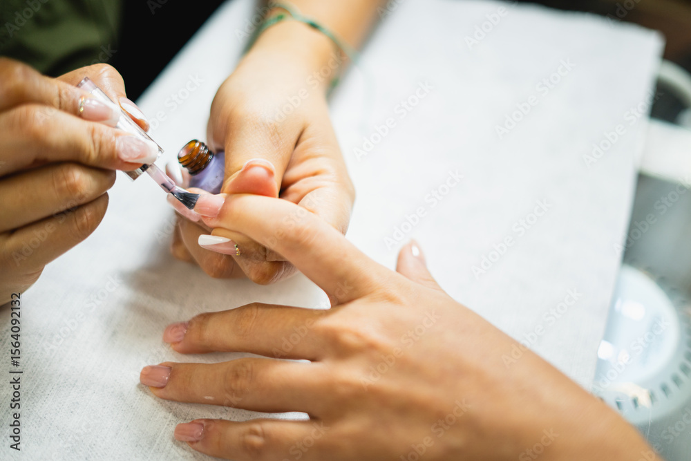 Obraz premium Manicurist working on client's hands at nail salon, cleaning old polish and applying semi-permanent nails