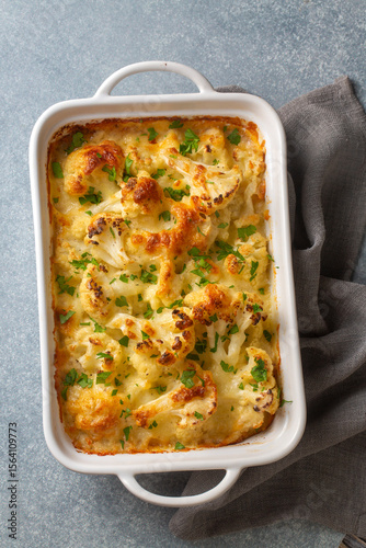 Casserole Cauliflower baked with cheese sauce in a pot close-up on a wooden table. Horizontal top view from above. Cauliflower gratin