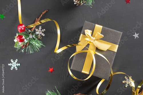 Christmas gift with gold ribbon on black background. Christmas top view