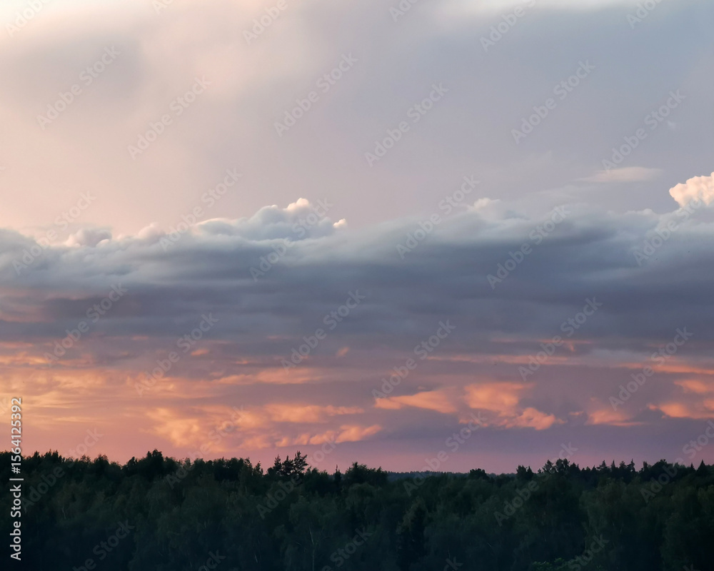 Fototapeta premium Dramatic sunset over a lush forest landscape, with vibrant hues of orange and pink illuminating the sky, creating a serene and tranquil atmosphere in nature's beauty