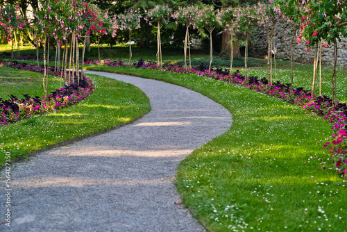 Fotografie Winding garden path surrounded by pink and purple blossoms, a serene natural setting perfect for peaceful walks and relaxation