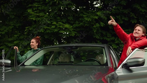  family traveling by car, husband showing his wife something interesting and beautiful, stop on the trip, they smile, happy family