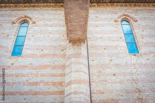 historic architecture with symmetrical windows, a close-up view of a historic brick wall with two symmetrically placed arched windows featuring blue glass panes