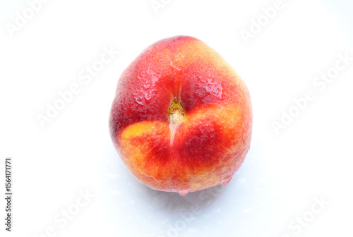 Flat peach isolated on white background. One fig peach in water drops. Fresh tasty peach