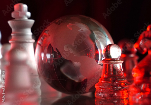 Crystal planet Earth amidst chess pieces showing the American continent, representing concepts of geopolitics, global power, competition for control, international relations, world leaders, struggle f