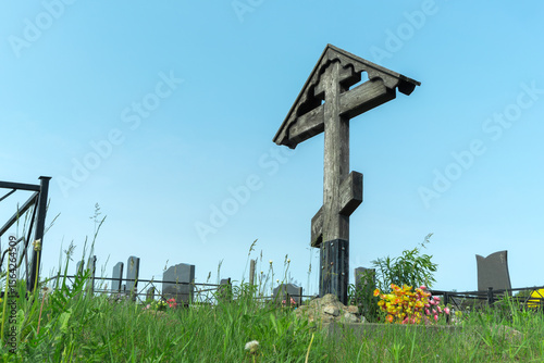 Old wooden cross standing tall in a peaceful resting place reflecting the beauty of life and the inevitability of death. Wooden cross in a serene cemetery landscape.