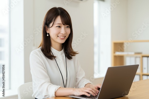 デスクでラップトップを操作する女性ビジネスパーソン。彼女は画面に真剣な眼差しを向け、知的な集中力を発揮し、業務に没頭している。