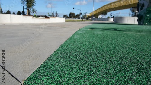Close-up view of a green soft rubber playground or outdoor gym surface next to a concrete pavement in a modern urban park in Australia. A well-designed public recreational space with safer surfacing. 