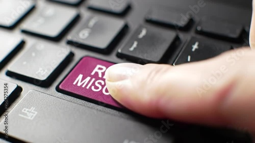 Close Up of Finger Pressing Magenta Report Misconduct Key on Black Laptop Keyboard with White Letters in Balanced
