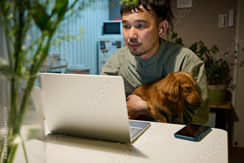 家で犬とリモートワークをする男性