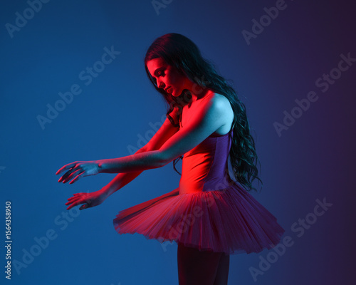 Dramatic 3/4 portrait of ballerina in red tutu and pointe shoes under moody blue and red neon lighting, expressive theatrical pose in artistic studio with cinematic contrast and vivid colour
