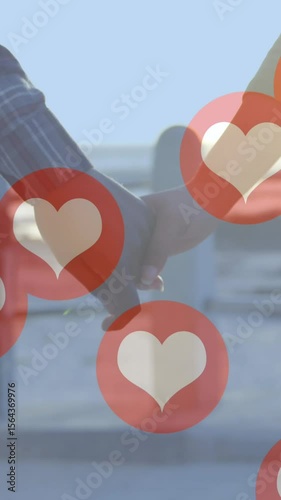 Multiple red heart icons floating against mid section of couple holding hands and walking