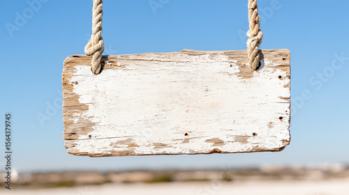 A blank wooden signboard hanging from twine against a clear blue sky, perfect for providing customizable messages.