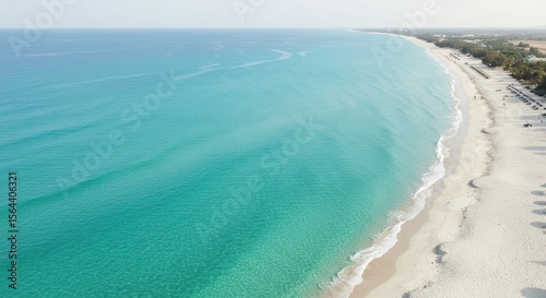 Aerial view of a serene beach with turquoise waters and gentle waves under a clear sky