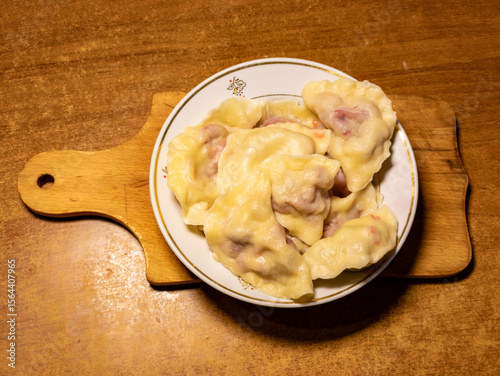 A plate of dumplings on a wooden cutting board on a table