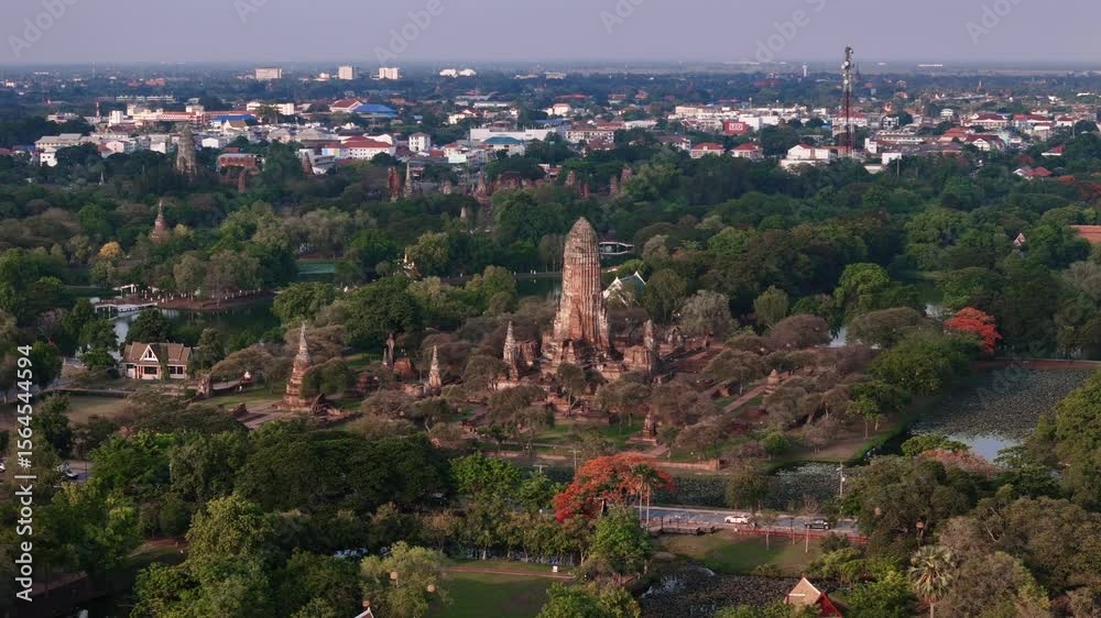Aerial cinematic motion to Wat Phra Ram temple ruins surrounded by canals and trees in ancient Ayutthaya city at sunset