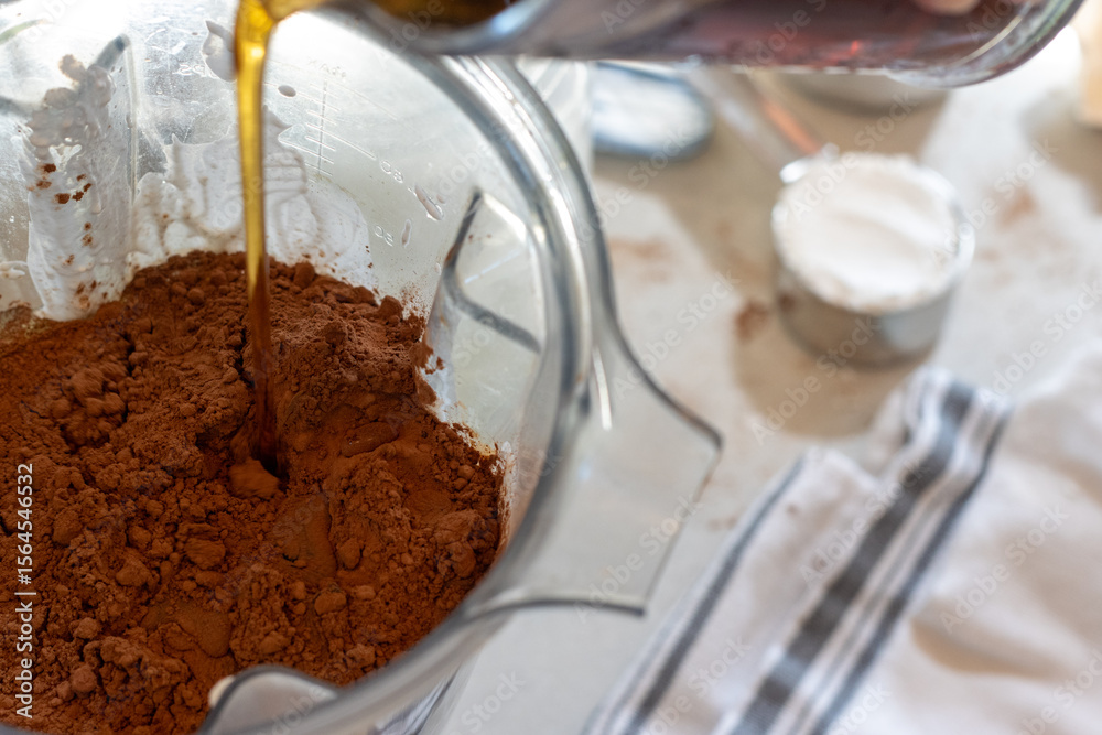 Fototapeta premium Maple syrup poured over cocoa, eggs and batter in blender jar