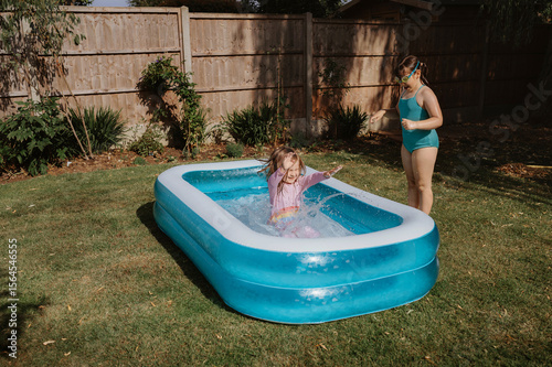Siblings playing in inflatable backyard pool