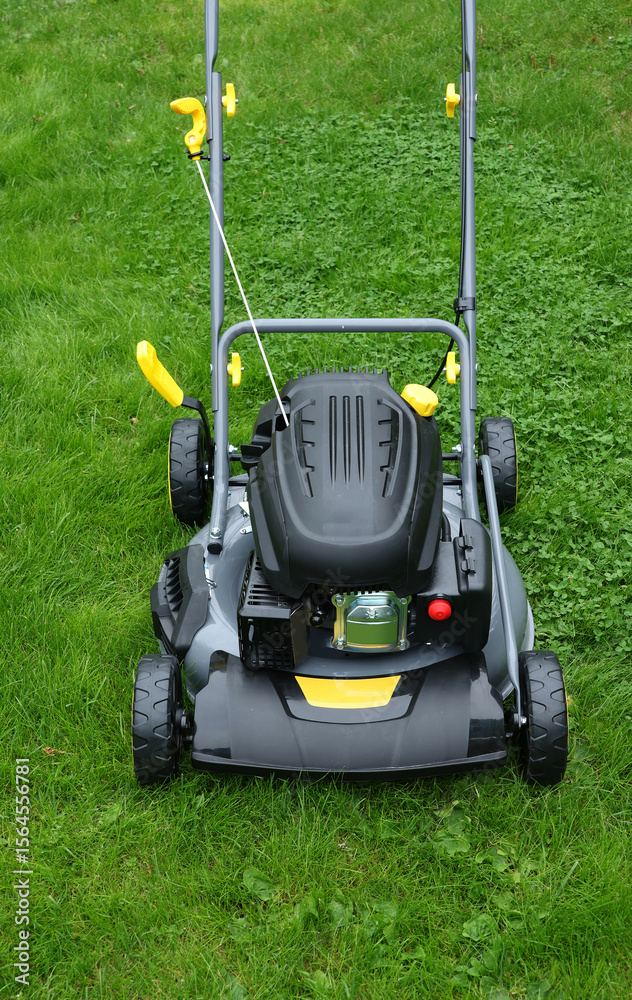 Fototapeta premium Brand new lawnmower in long grass, ready for work