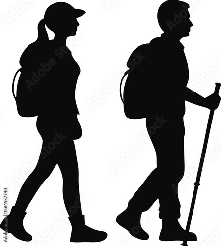 Silhouettes of a man and woman hiking together with backpacks and a walking stick