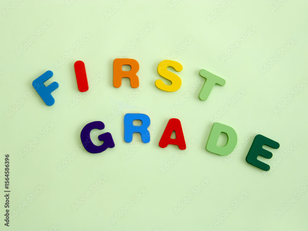 Obraz premium The multi colored wooden letters form the expression First grade, referring to school days.