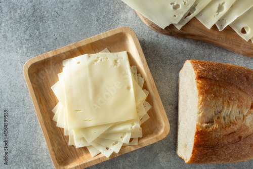 A top down view of a stack of thin slices of American style Swiss cheese, on a plate.