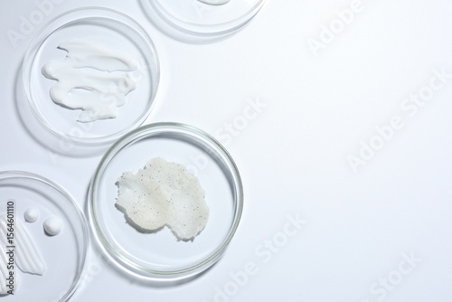 Different cosmetic products in Petri dishes on white background, flat lay. Space for text