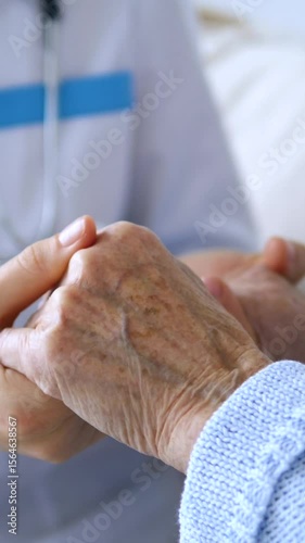 Vertical screen compassionate physician gently holding senior patient's hand, providing emotional support during healthcare consultation