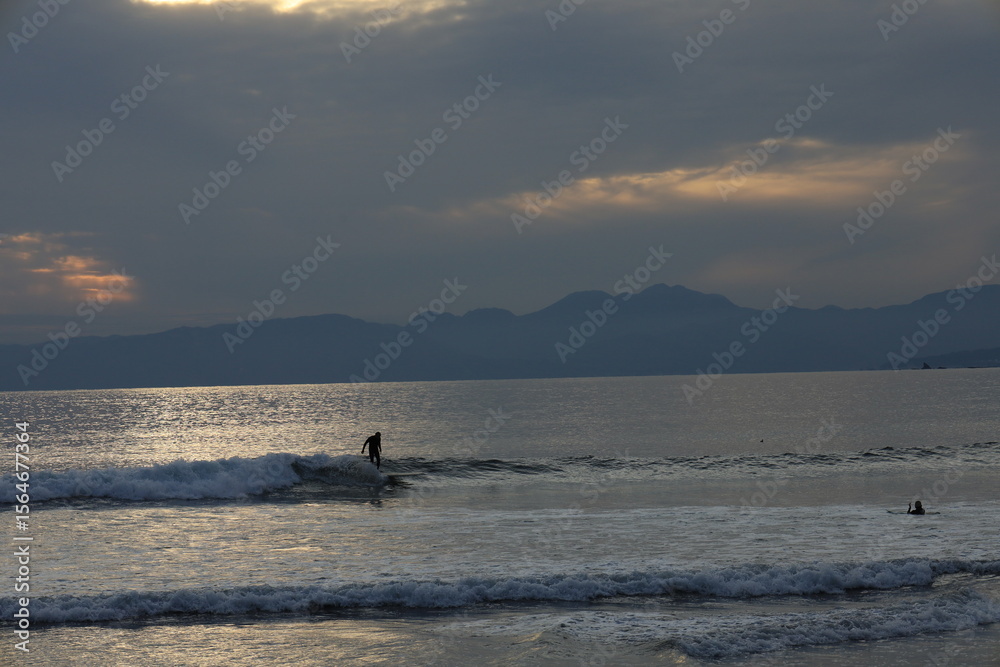 Fototapeta premium 江ノ島近くの片瀬漁港西プロムナードから日没後に青みかかる富士山のシルエットと海のある風景