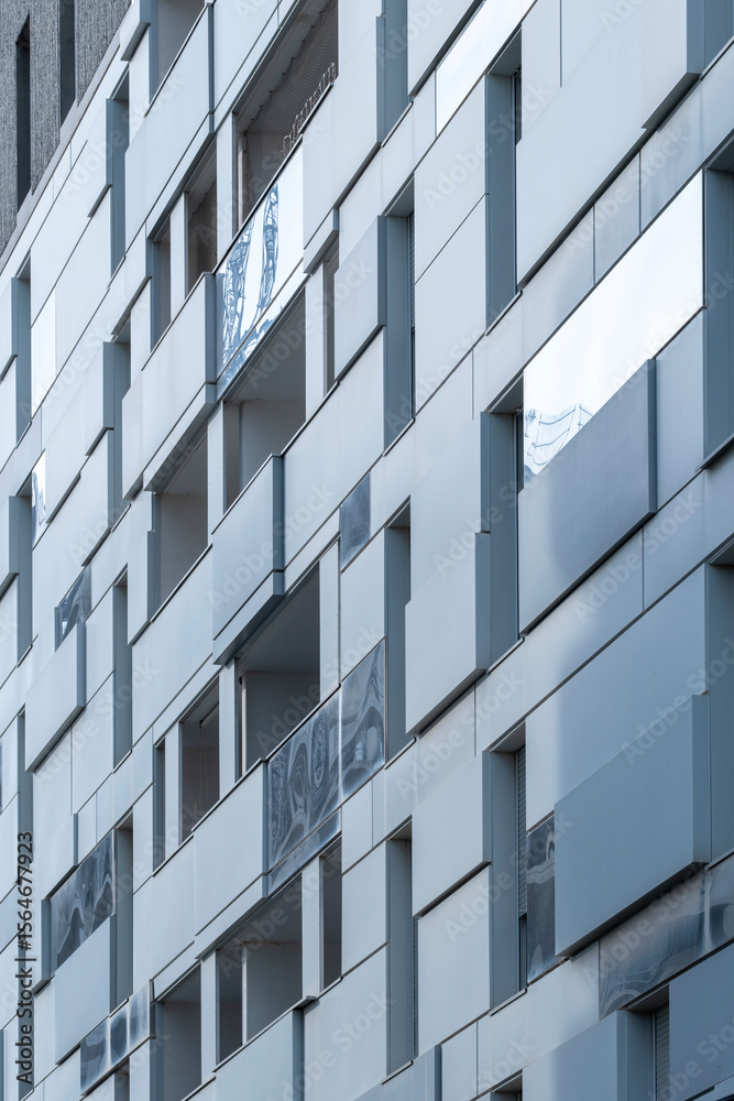 Modern urban facade composed of metallic rectangular modules reflecting light under blue sky, showcasing geometric patterns, contemporary architecture, and minimalist urban design aesthetics Modern urban facade composed of metallic rectangular modules reflecting light under blue sky, showcasing geometric patterns, contemporary architecture, and minimalist urban design aesthetics