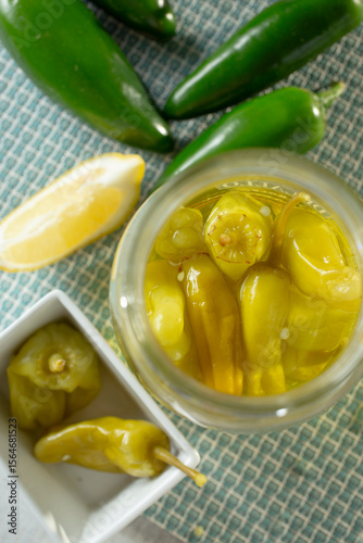 A top down view of pepperoncini peppers in a glass jar.