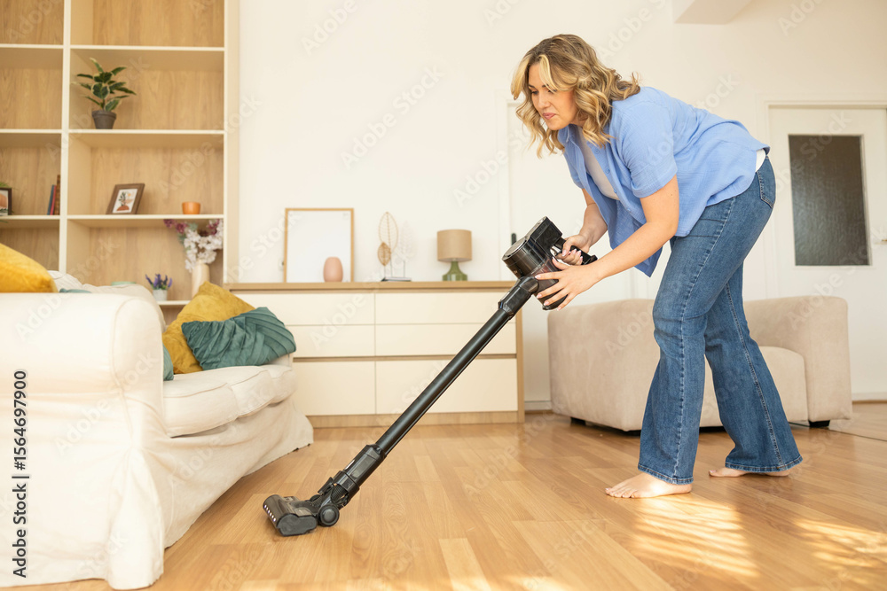 Fototapeta premium A woman diligently vacuums her living room, emphasizing the importance of cleanliness and a tidy home environment.
