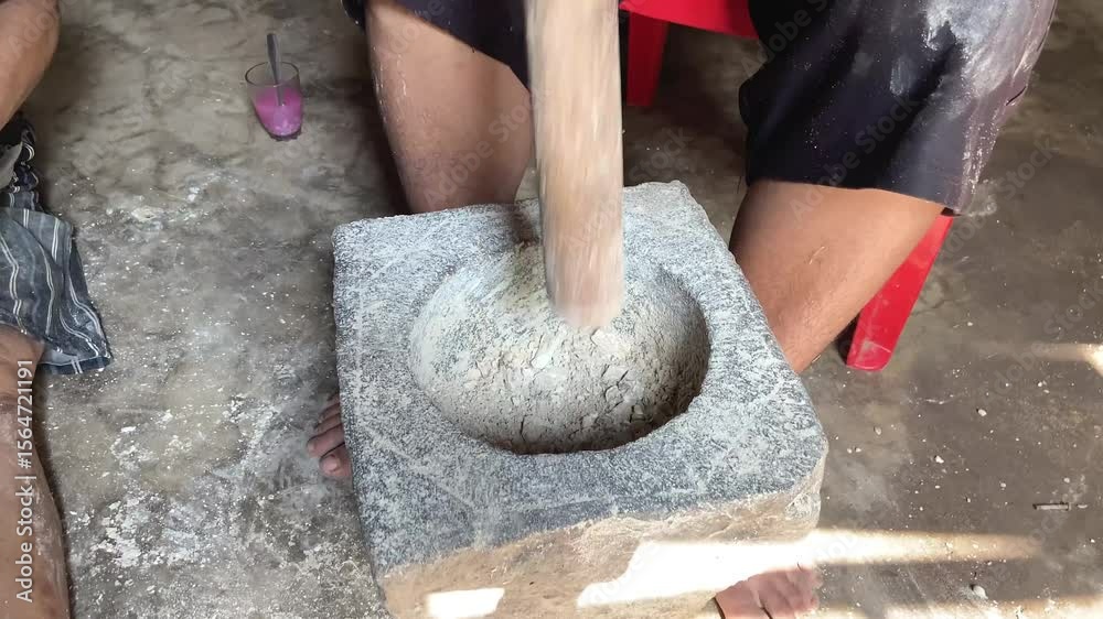 jarak dekat, seorang pria yang sedang menumbuk, dengan lesung batu dan kayu tradisional