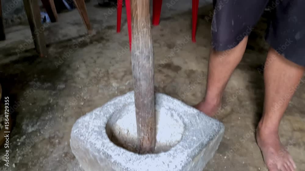 jarak dekat, seorang pria yang sedang menumbuk, dengan lesung batu dan kayu tradisional