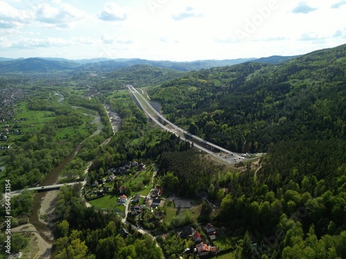 Fototapeta Naklejka Na Ścianę i Meble -  Budowa drogi ekspresowej S1 między Węgierską Górką a Milówką widziana z drona w wiosenny dzień. Construction of the S1 expressway between Węgierska Górka and Milówka captured by drone on a spring day 