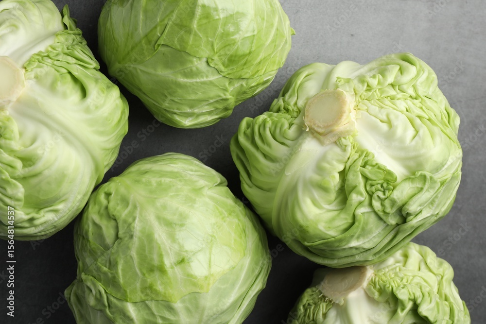 Fototapeta premium Fresh green cabbages on grey table, flat lay