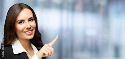 Banner wide image - happy smile businesswoman showing pointing advertise. Business woman executive employee bank manager, against blurred office background with free ad text space