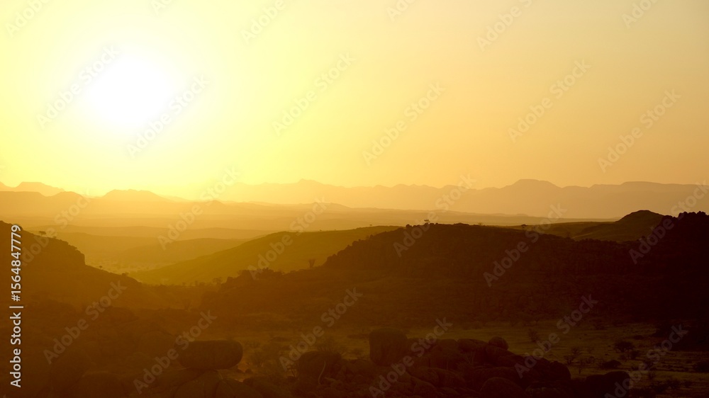 Golden desert sunset over rugged mountain silhouettes in Namibia, with glowing sunrays casting soft light across the vast, arid landscape, damaraland Golden desert sunset over rugged mountain silhouettes in Namibia, with glowing sunrays casting soft light across the vast, arid landscape, damaraland