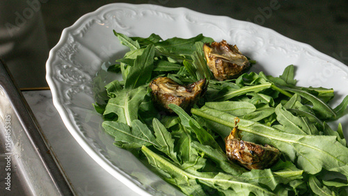 Slika na platnu Grilled artichokes nestle on peppery arugula, a dance of bitter and earthy tones