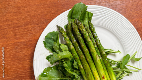 Canvas-taulu Grassy spears of asparagus entwine with peppery arugula, evoking springtime rene