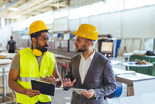 Industrial Engineers Collaborating in a Factory Setting with Safety Gear
