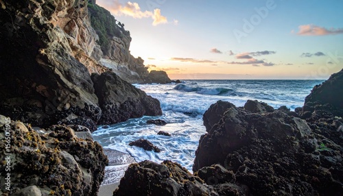 Rocky beach alcove at sunset, ocean waves crashing onto shore
