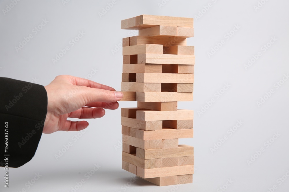 Lviv, Ukraine - December 04, 2023: Woman playing Jenga on light gray background, closeup Lviv, Ukraine - December 04, 2023: Woman playing Jenga on light gray background, closeup